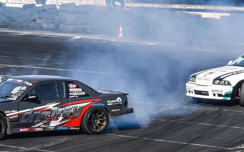FWD car drifting on a track Front-wheel-drive car sliding sideways through a turn with tire smoke on a track
