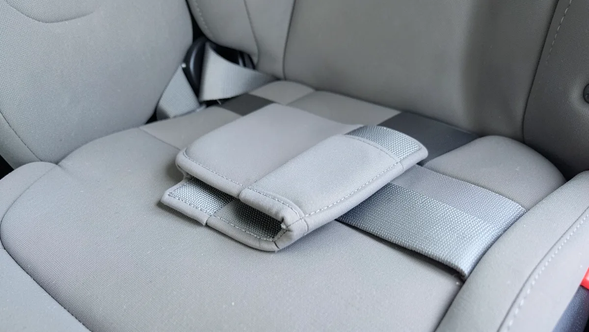 Padded shoulder harness strap resting against an empty child car seat cushion