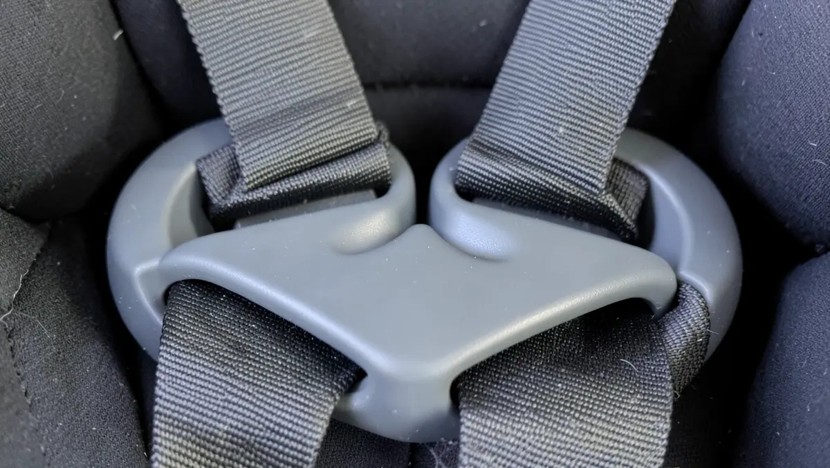 Close-up of the front harness adjuster strap and splitter plate between the leg area of a child car seat