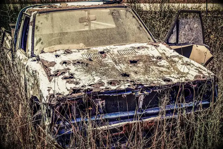 Rusted car hood with peeling paint needing repair