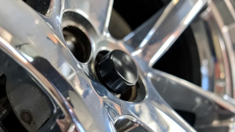 Black anodized aluminum tire valve cap installed on a car alloy wheel valve stem