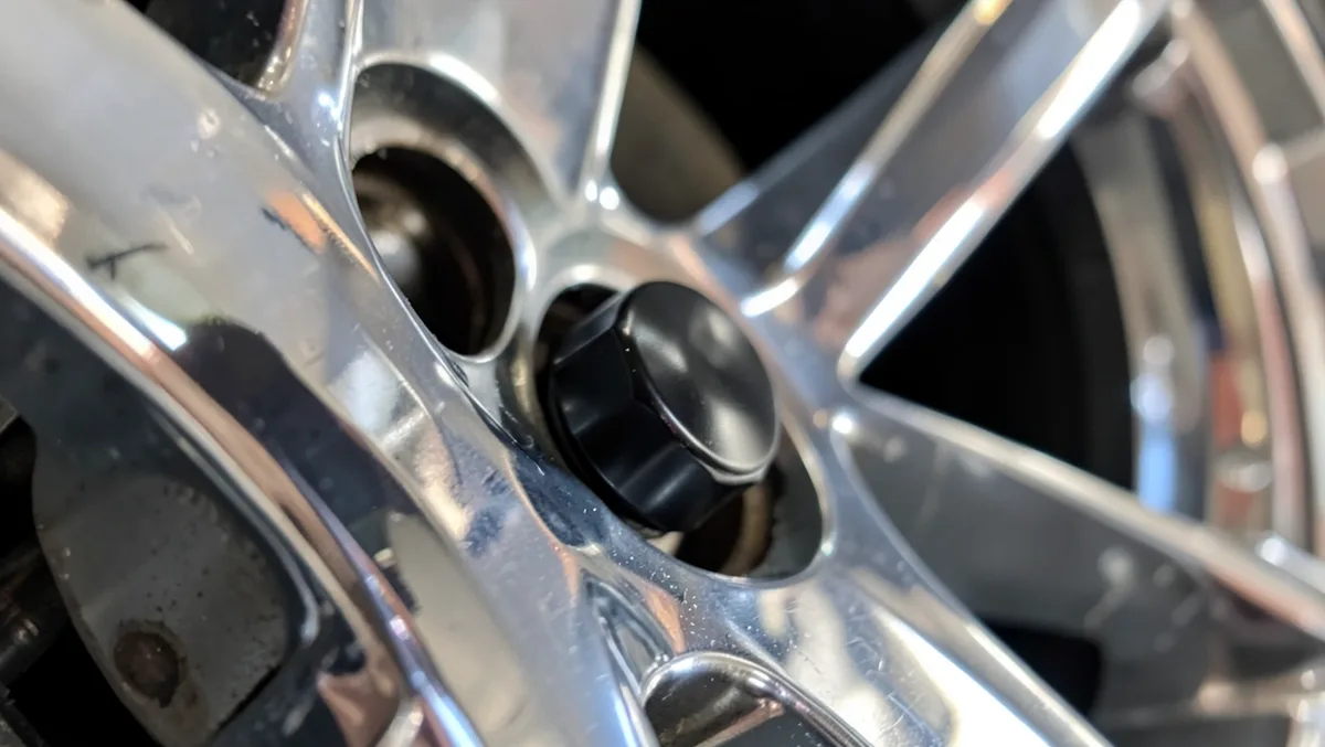 Black anodized aluminum tire valve cap installed on a car alloy wheel valve stem