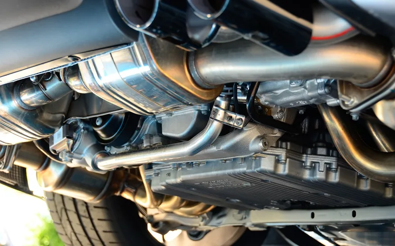 Underside of a car showing exhaust pipes, a muffler and the tailpipe tips