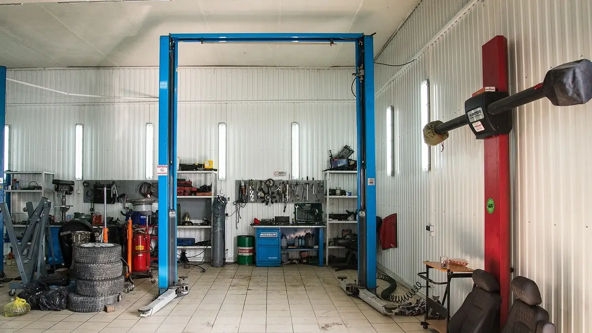 Empty auto service bay with a blue two-post vehicle lift and stacked tires
