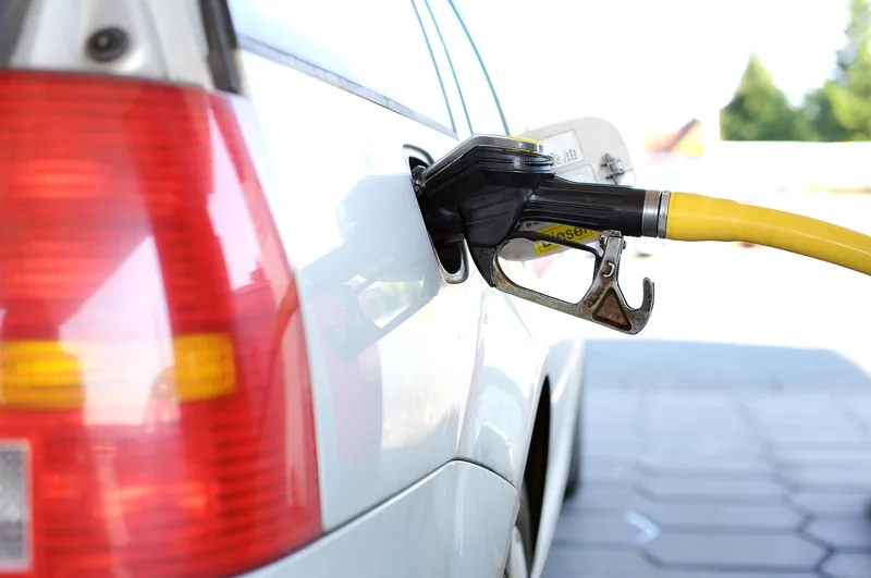 Yellow fuel hose and nozzle inserted into a car fuel filler with an automatic shut-off valve
