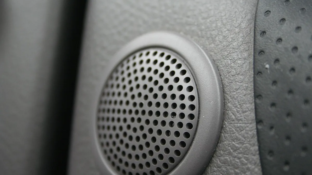 Close-up of a round perforated speaker grille on a car door panel