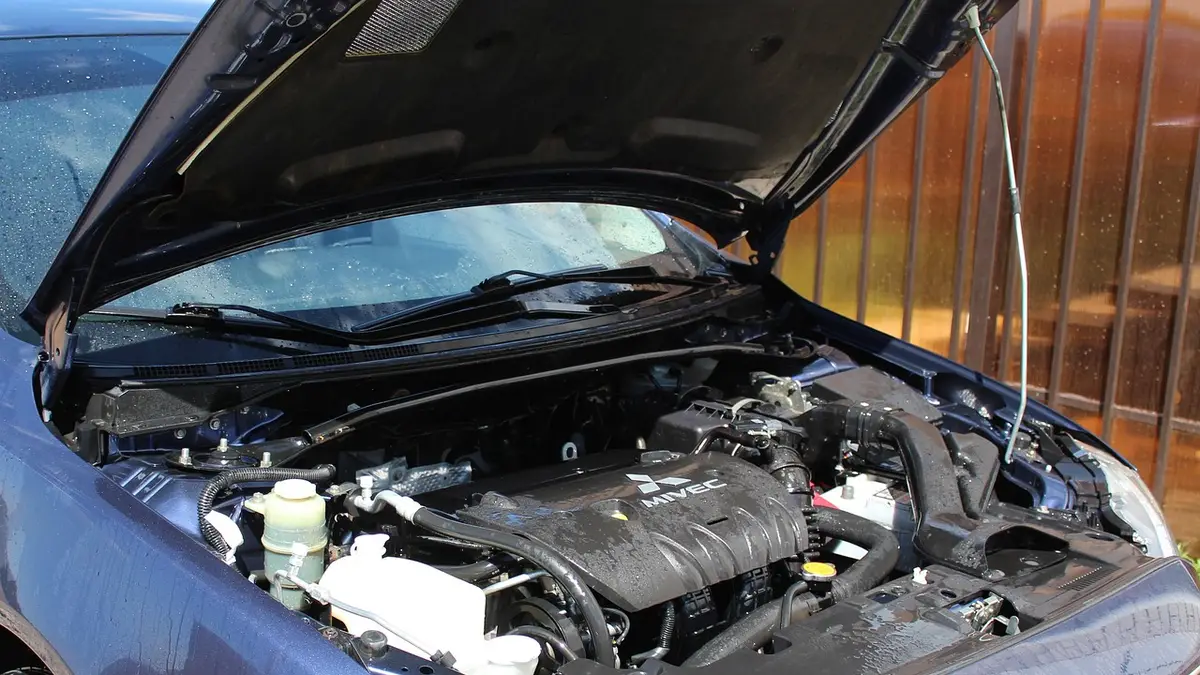 Mechanic inspecting a car engine bay for melted plastic and overheating electrical components