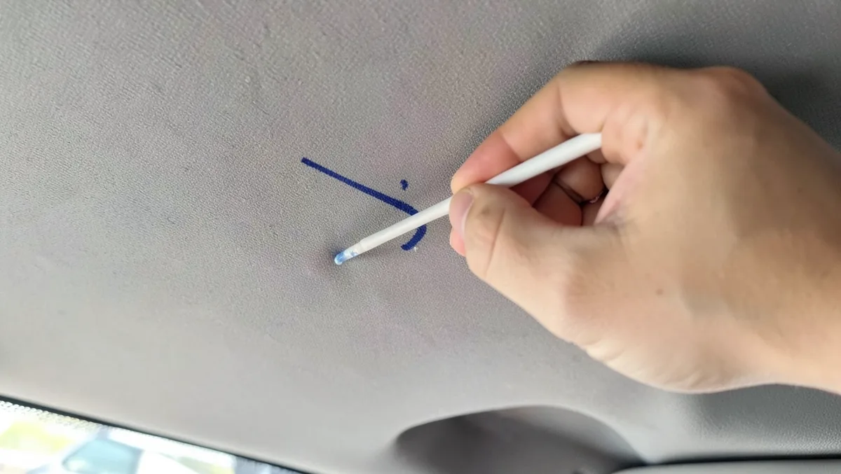 Dabbing an ink pen stain on a car headliner with a rubbing-alcohol cotton swab
