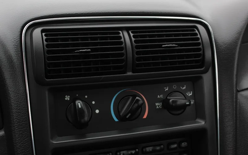 Close-up of a car dashboard and center console where a window fan supplements airflow