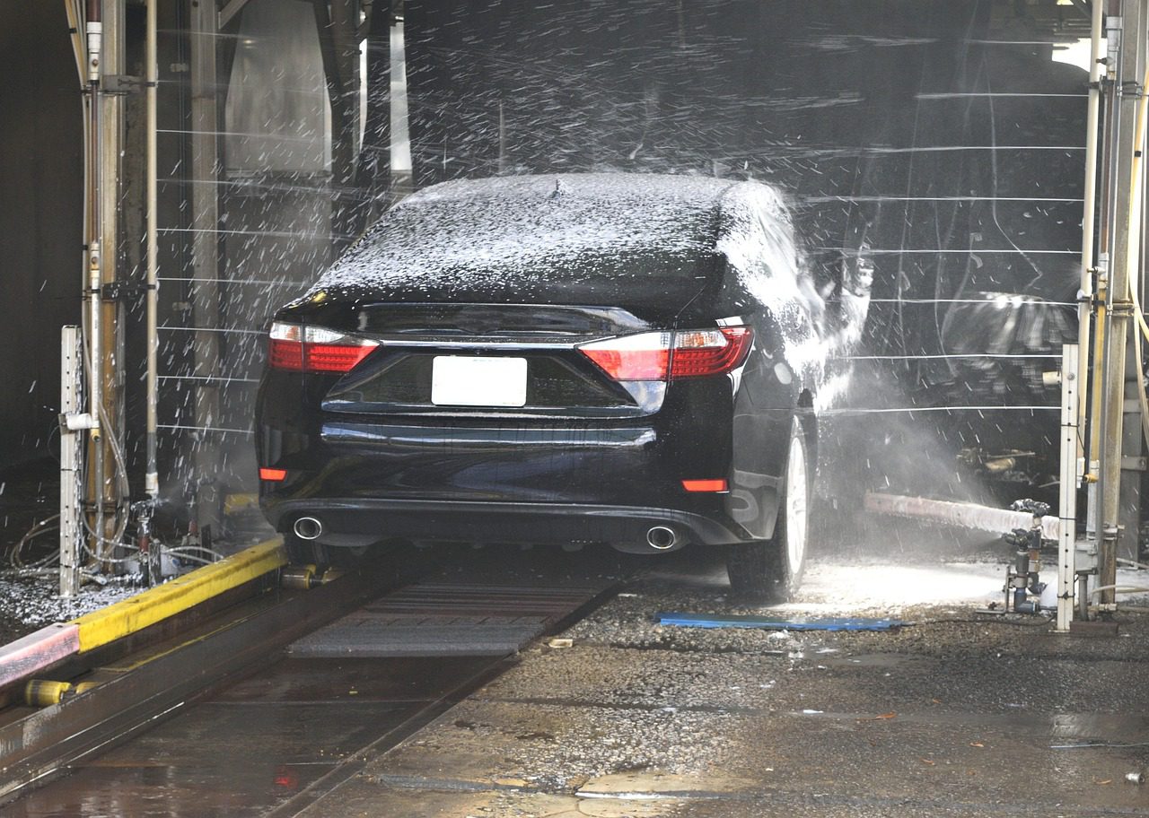A car being washed with soap and a sponge, using the two-bucket method to avoid scratching the paint