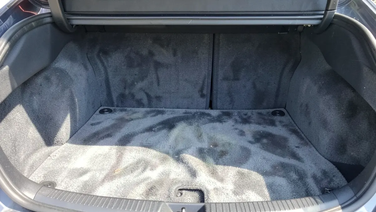 Worn faded gray carpet in a car trunk before dyeing