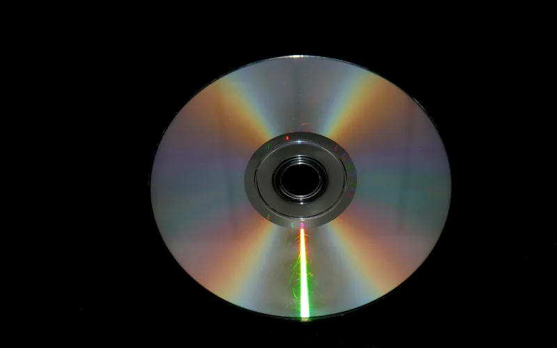 Compact disc lying on a black surface showing its reflective underside
