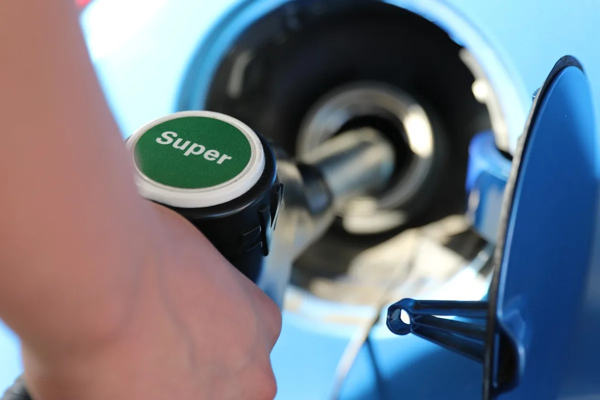 Close-up of a fuel pump nozzle inserted in a car fuel filler neck