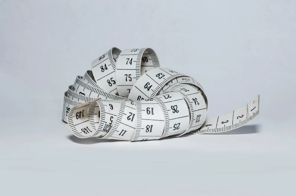 A white measuring tape coiled on a plain background