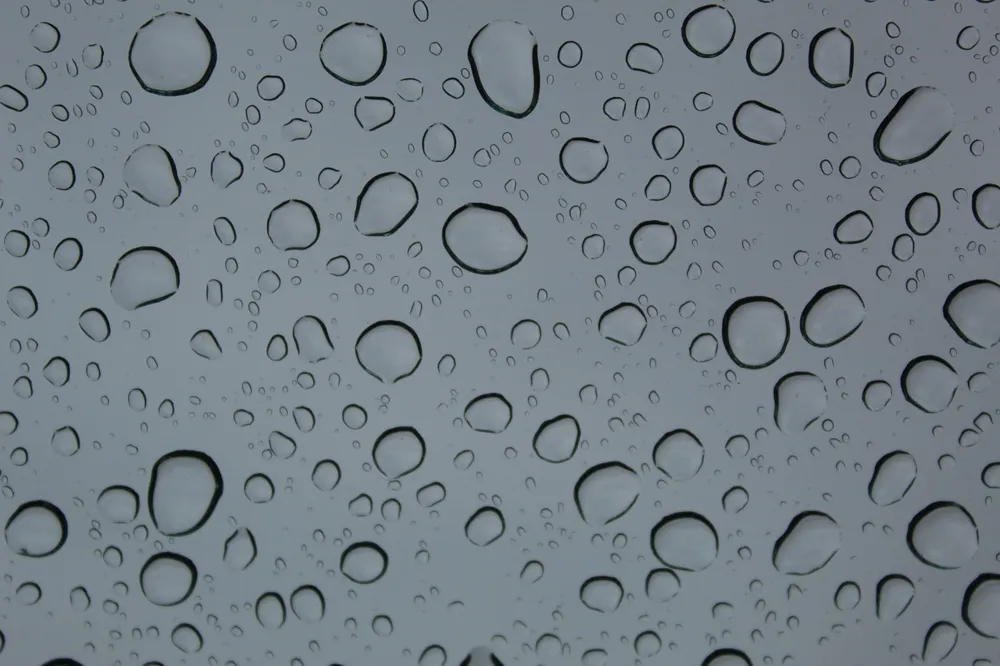 Water droplets on a glass pane against a grey sky