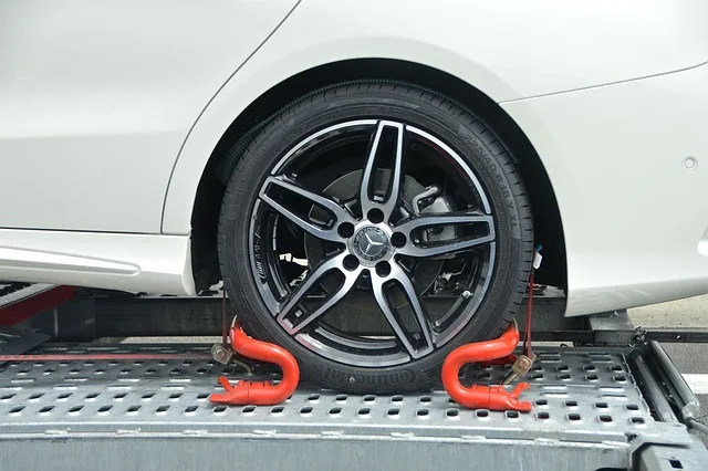 car wheel secured with tow hooks on a flatbed tow truck