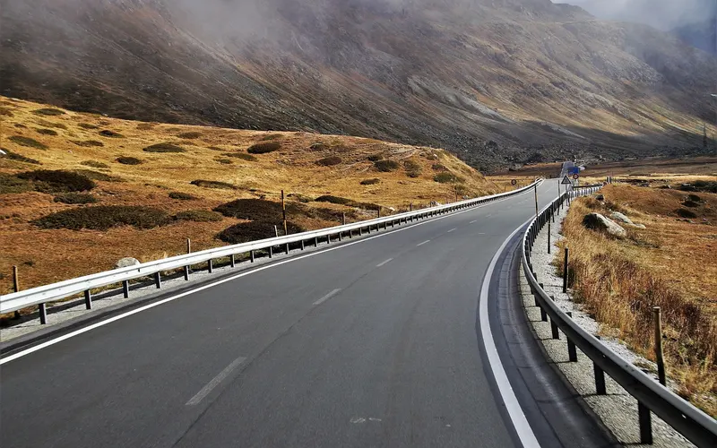 Empty paved mountain road with a guardrail and white lane markings