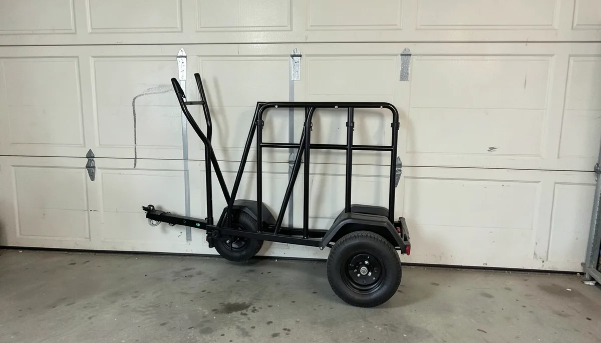 Small folding utility trailer collapsed and stored upright against a garage wall