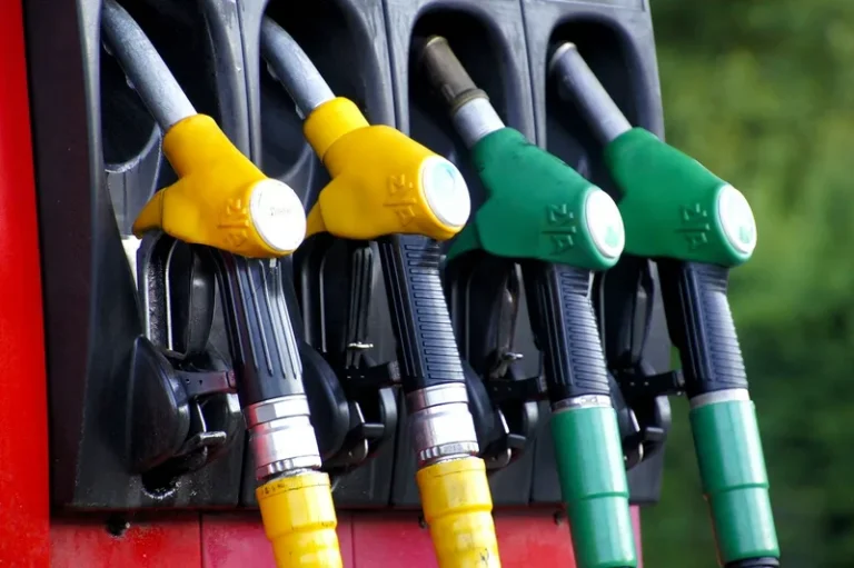 Row of gas pump nozzles at a fuel station with yellow regular and green premium grades