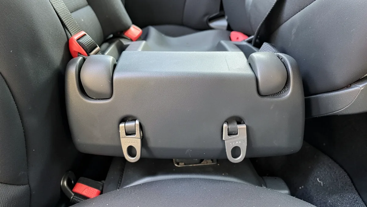 Close-up of a Graco infant car seat base LATCH hooks clipped to the lower anchors in the back seat
