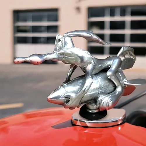 BEMKWG Coyote Trucks hood ornament, chrome cartoon-style metal rocket design mounted on a red car hood