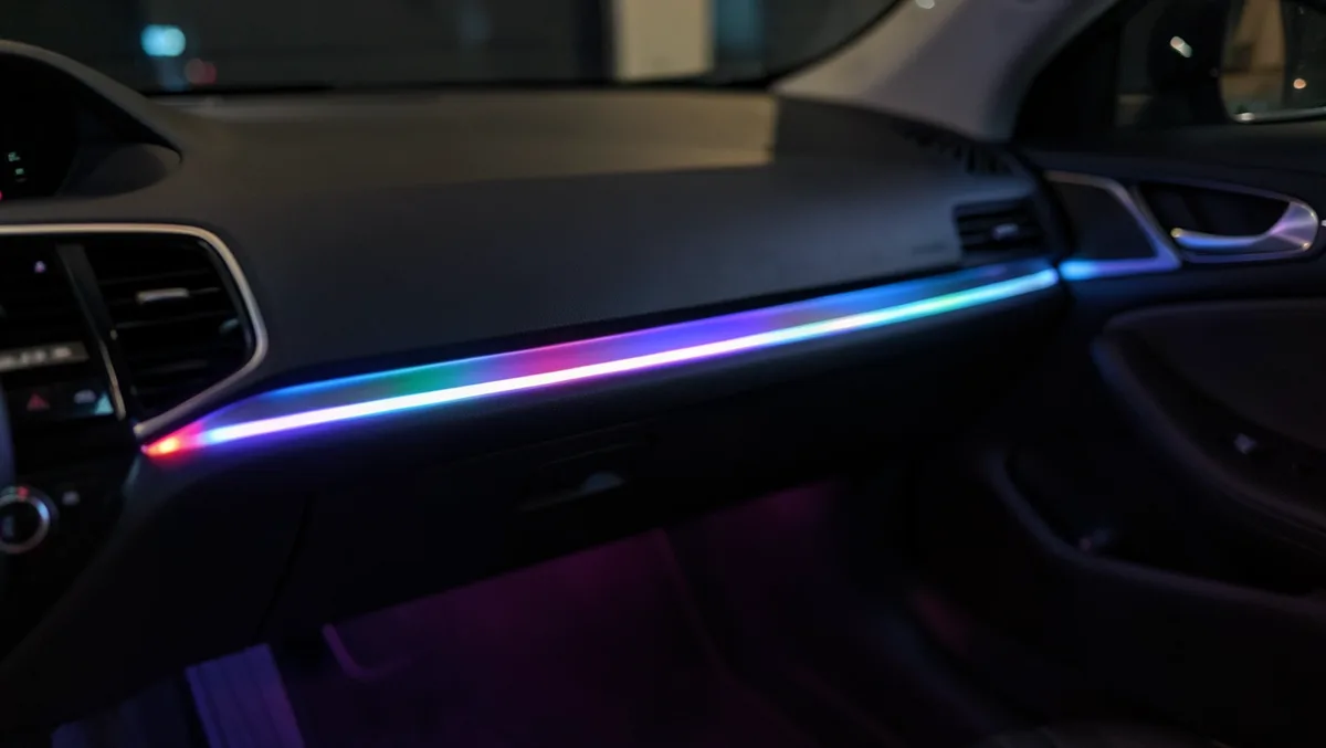 Multicolor RGB LED ambient light strip glowing along a car dashboard seam at night