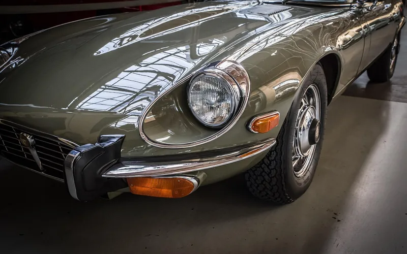 Front wing and headlight of a classic Jaguar E-Type in a showroom