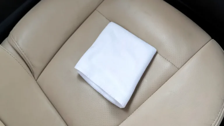 White microfiber cloth resting on a beige leather car seat for cleaning