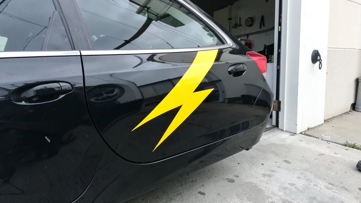 Yellow lightning bolt vinyl decal applied to the rear door and quarter panel of a black car