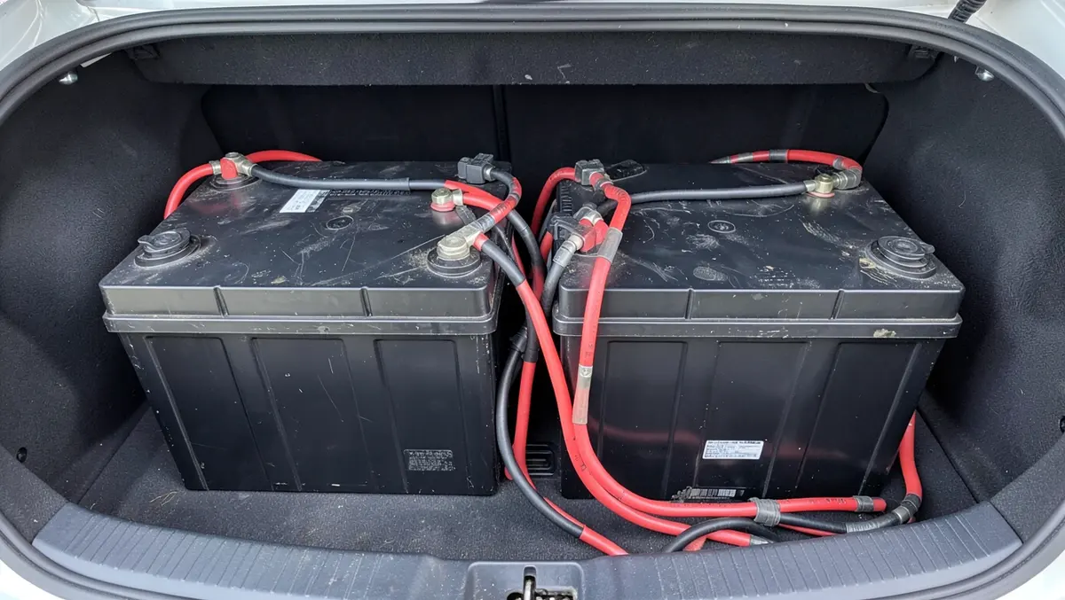 Two car batteries connected with heavy gauge cables showing a dual battery car audio wiring setup