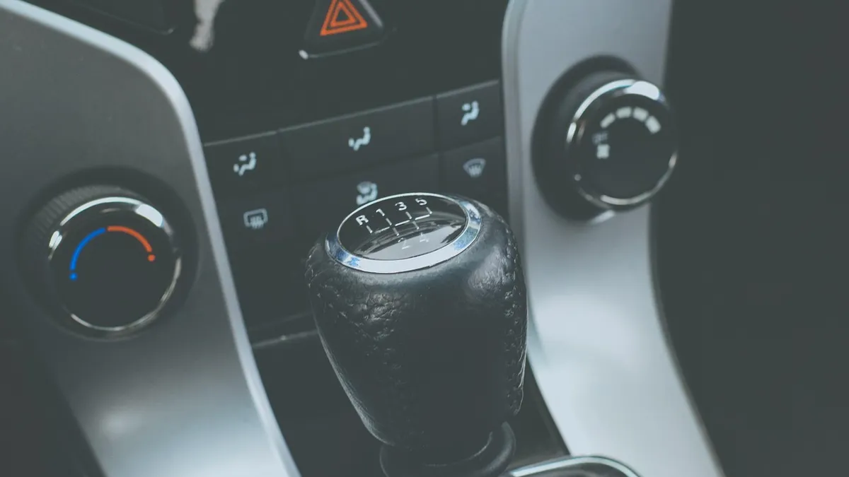 Driver shifting a manual transmission gear stick while driving