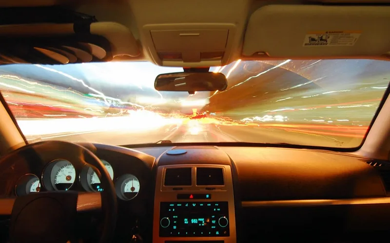 Night driving view through a car windshield showing headlight glare and light trails on the highway Night driving view through a car windshield showing headlight glare and light trails on the highway
