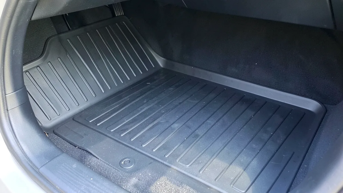 Black heavy-duty rubber trim-to-fit floor mat installed in a car footwell