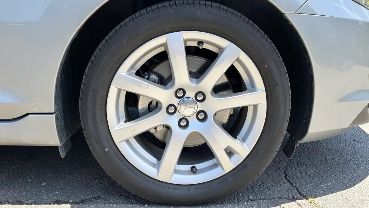 Close-up of a silver alloy wheel mounted on a car showing the lug nuts and spoke pattern