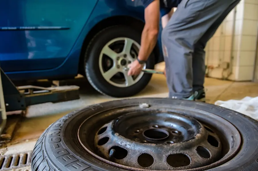 Tire service bay with a wheel off the car and a mechanic working at the wheel