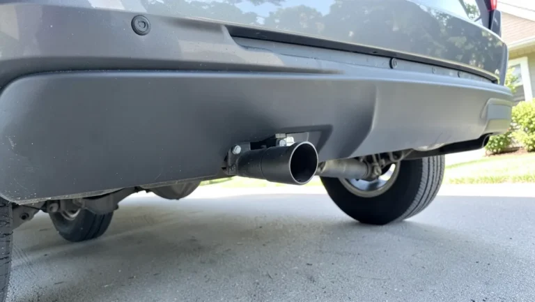 Trailer hitch receiver installed under the rear bumper of a car, ready to tow a U-Haul trailer