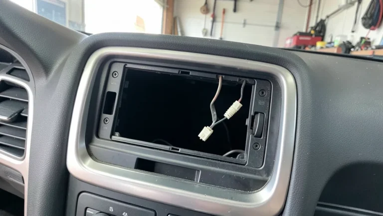 Empty single-DIN car stereo dash opening with wiring harness connector exposed after factory radio removal
