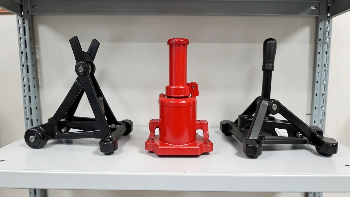 Three different car jacks - scissor jack, hydraulic bottle jack, and floor jack - displayed side by side on a store shelf