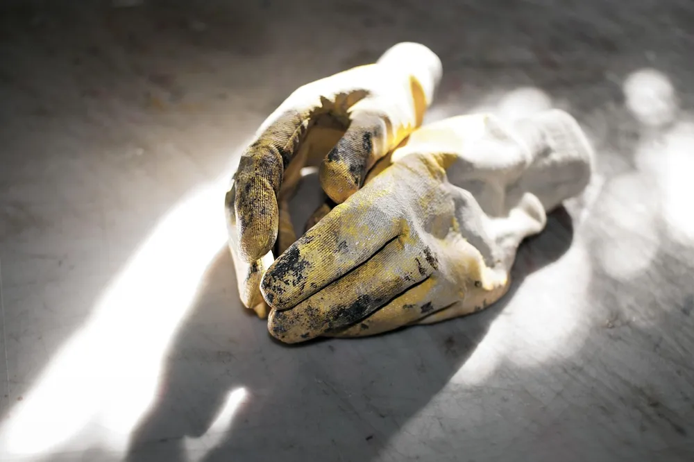 Pair of worn work gloves lying on a workshop floor
