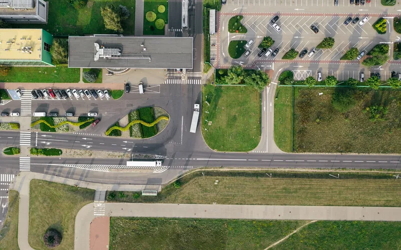 Aerial view of a parking lot with parked cars next to roads and a building