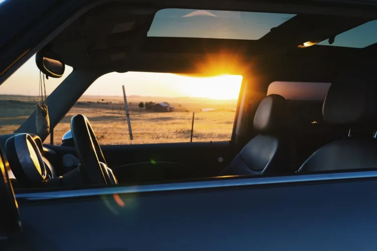 Car cabin seen through the window at sunset with a sunroof and headliner overhead