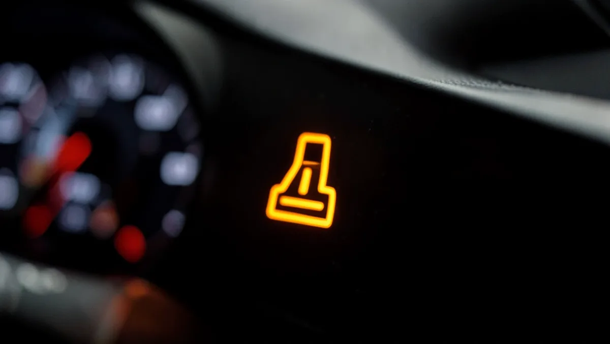 Illuminated amber warning light glowing on a car dashboard instrument cluster