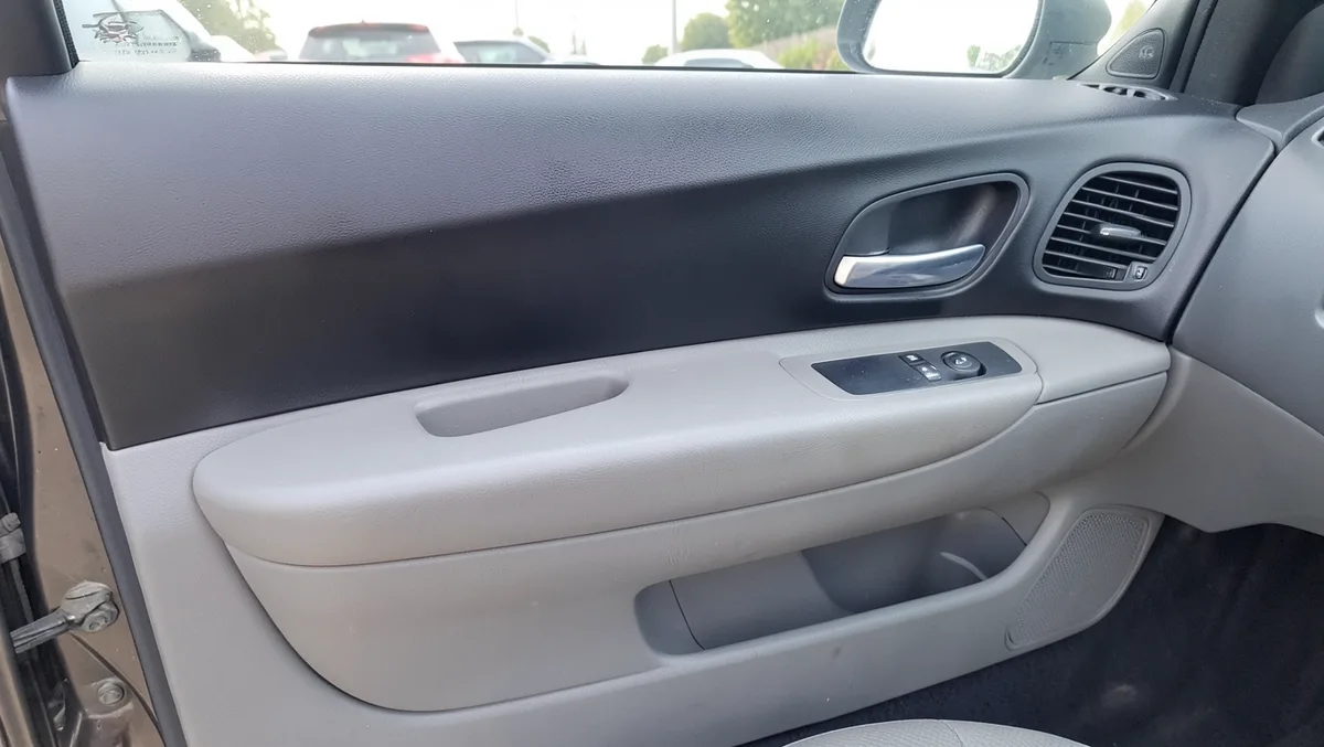 Car door panel partially resprayed matte black next to original faded gray plastic trim