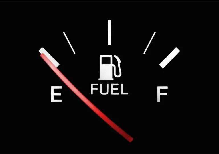Car fuel gauge needle resting near E with F at the right end of the dial