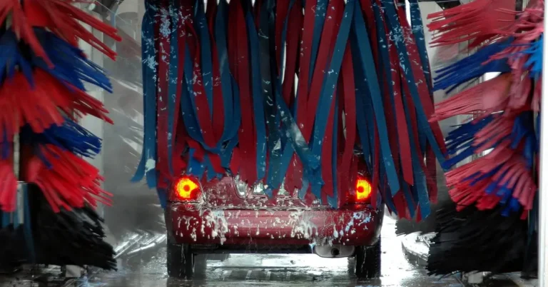 Car going through an automatic car wash tunnel between rows of red and blue brushes