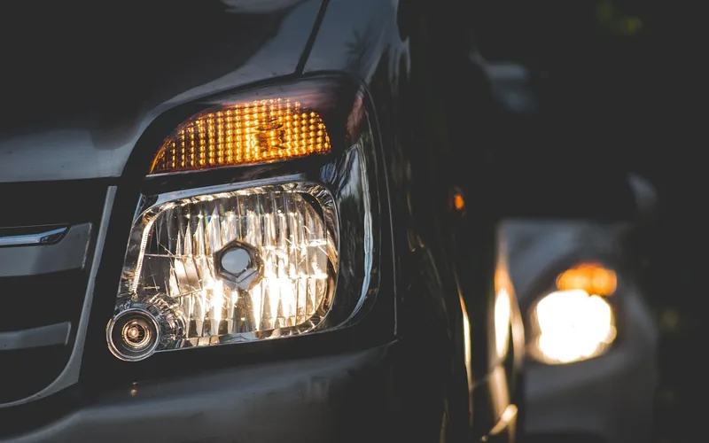 Car headlight lit at night on a dark street
