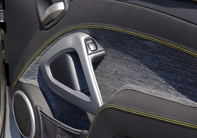 Interior door panel with a molded plastic handle trim and fabric insert