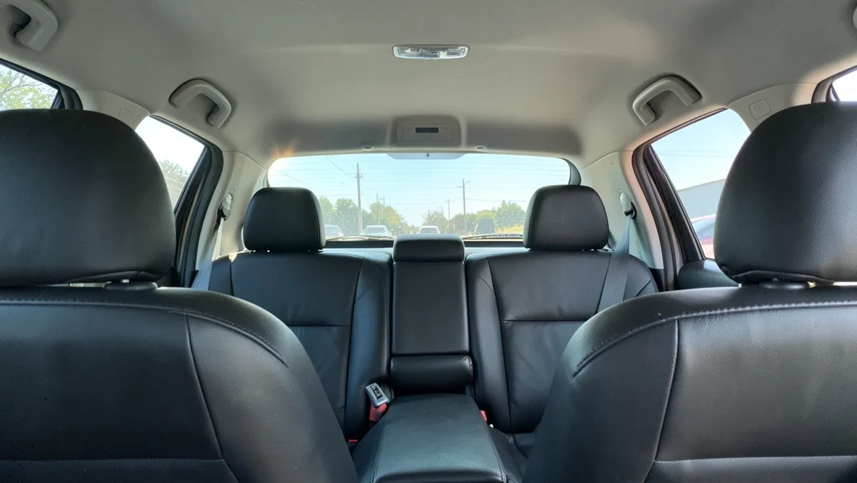 Bright sunlight streaming through a windshield onto black leather car seats