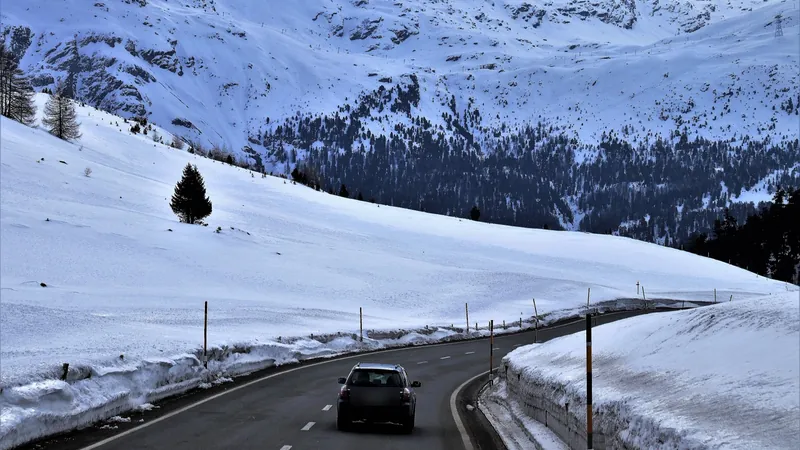 Car driving on a cleared mountain road between snowbanks in winter Car driving on a cleared mountain road between snowbanks in winter