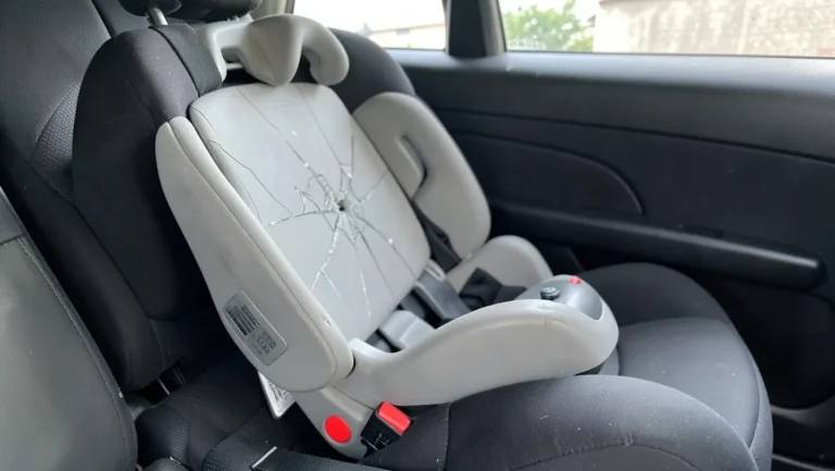Child car safety seat with a cracked plastic shell in the back seat after a car accident